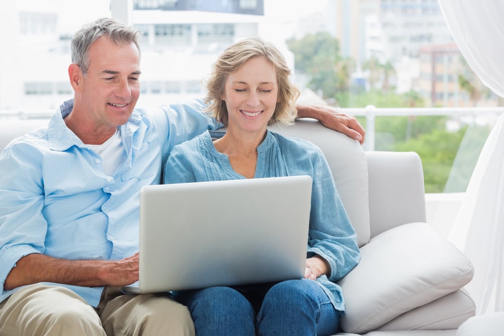 Cheerful couple relaxing on their couch using the laptop at home in the sitting room-1